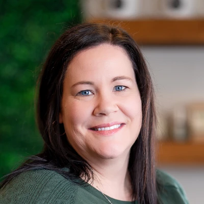 Close-up portrait of a person with dark hair wearing a green top