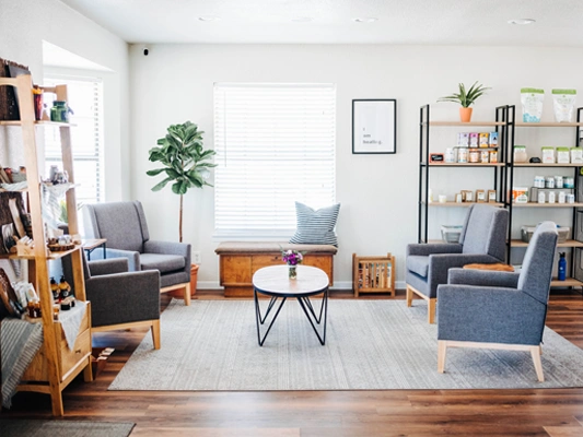 Bright, modern chiropractic waiting room with gray armchairs